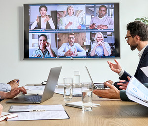 Employees on online conference video call on tv screen in meeting room.